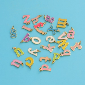 Colorful enamel A-Z letter pendants in gold titanium steel on light blue background
