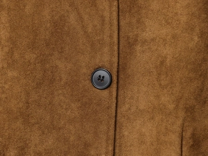 Macro view of dark brown suede jacket fabric with black matte button and fine stitching
