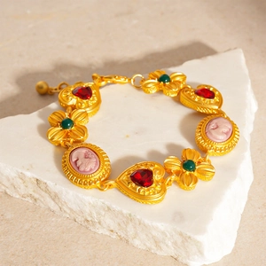 Detailed view of vintage gold bracelet with red heart gems and pink cameo charm