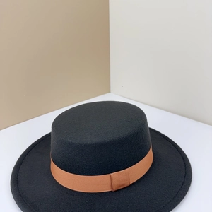 Close-up of black wool felt boater hat with a brown grosgrain ribbon and bow detail