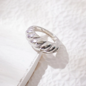 Polished silver twisted dome ring made of stainless steel on white geometric stone