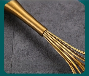 Detail of reinforced joint on golden stainless steel whisk with brushed metal finish