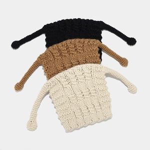 Detailed knit texture of crochet beanies in black, brown, and cream with braided straps
