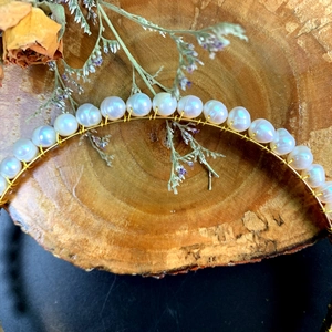 Detailaufnahme von handgewebten Naturperlen mit Golddraht auf einem Haarreif-Accessoire
