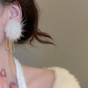 Detail of plush white pompom earrings with golden bead tassels and pearl flower design