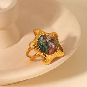 Macro detail of gold star ring with colorful natural stone inlay and textured edges