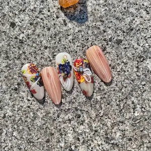 Press-on nails with vintage roses and 3D bow accents on a textured stone surface