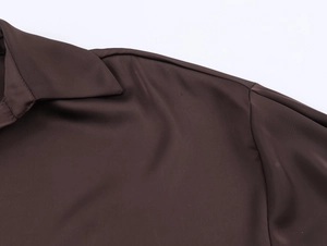 Gros plan du col en satin et des coutures d'épaule sur cette chemise marron foncé