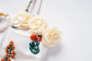 Détail de maillot de bain floral avec roses 3D crème et anneaux métalliques décoratifs