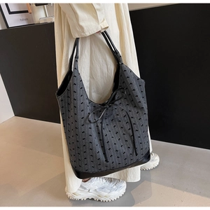 Detailed side view of grey fabric tote bag with black leather trim and large ribbon bow