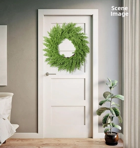 Close-up of lush 20-inch green pine needle wreath hanging on a white interior door