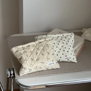 Quilted corduroy cosmetic bags with floral and heart patterns shown on a plush surface