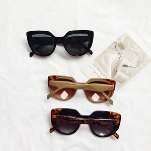 Three pairs of retro cat-eye sunglasses in black and tortoiseshell on white cloth