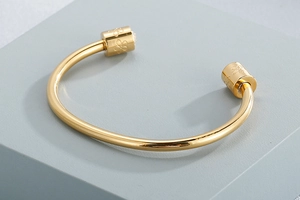 Macro detail of gold open cuff bangle with cylindrical engraved floral tips and crystal