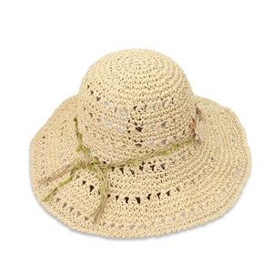 Detail of hollow-out straw sun hat with floral decoration and green leaf ribbon
