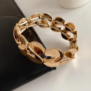 Macro shot of gold S-shape elastic bracelet with brushed metal texture on leather