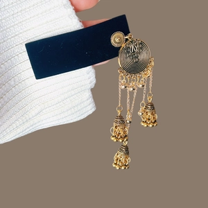 Détail macro de boucles d'oreilles bohème dorées avec motifs spirales et grelots