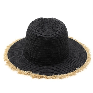 Detail of black woven sun hat featuring natural raffia frayed edges for beach vacations