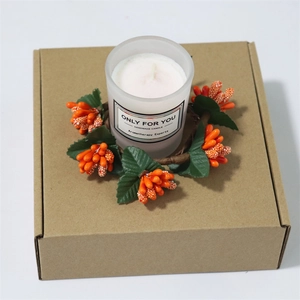 Detail of a handmade scented candle set with an orange berry wreath in a kraft gift box