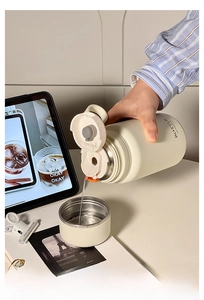 Detail of hand pouring tea from a cream insulated flask with a built-in cup lid