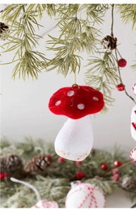 Close-up of red and white mushroom ornament with flocking texture on a pine branch