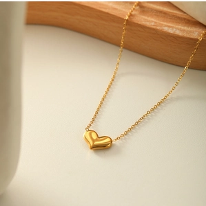 Detail view of a 3D heart pendant necklace in gold finish with a delicate chain