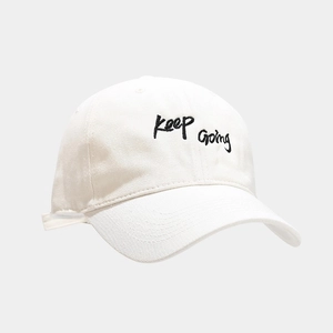 Close-up of black 'Keep Going' embroidery on a premium white cotton baseball cap