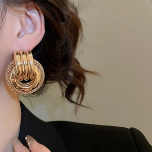 Gros plan de boucles d'oreilles rondes dorées multicouches avec texture en maille sur modèle