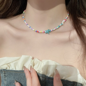 Close-up of colorful beaded necklace with a blue starfish pendant and daisy flower detail