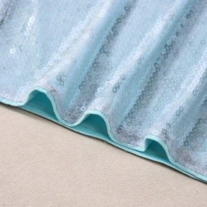 Détail macro des paillettes bleu clair et blanches sur un haut sans manches ajusté