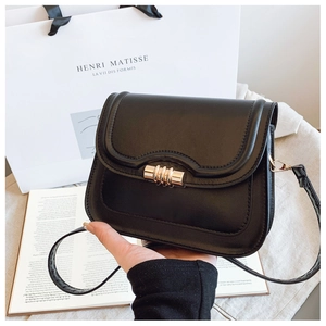 Détail d'un sac à main noir en cuir avec fermoir rotatif doré et texture élégante