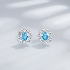 Macro shot of silver flower earrings with sky blue gemstone and white zircon halo