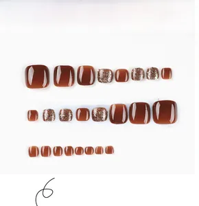 Macro view of 24 coffee brown and silver glitter press-on toe nails on white background
