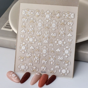 Detailed view of 5D embossed nail stickers with white floral patterns and gold accents
