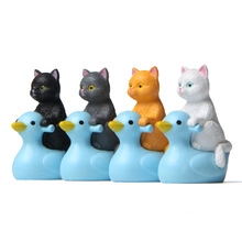 Detailed view of four resin cat figurines riding blue ducks in black, grey, orange and white