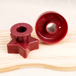 Detail of red plastic donut mold with star and round cutters on a wooden board