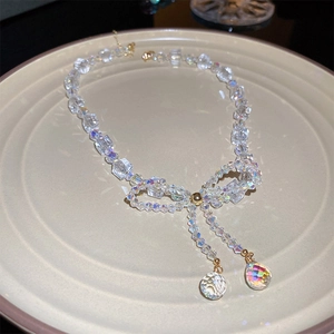 Detailed view of iridescent bow necklace with faceted crystal beads and gold teardrops
