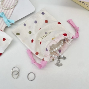 Détail d'un sac à cordon avec pois colorés et collier de perles élégant à l'intérieur
