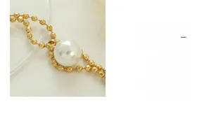 Detailed close-up of a large white pearl paired with a sleek gold-plated chain link
