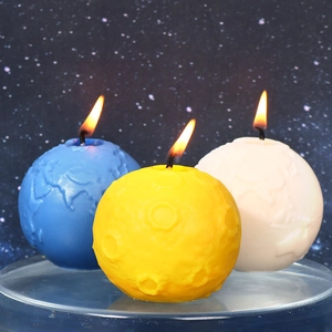 Tre candele accese a forma di pianeti Terra e Luna su sfondo a tema stellare scuro