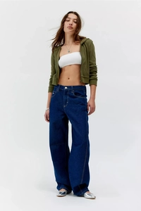 Vue complète d'un jean large délavé bleu porté avec un sweat à capuche vert olive