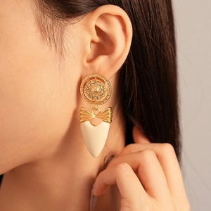 Détail de boucles d'oreilles vintage avec nœud et cœur doré sur un mannequin femme