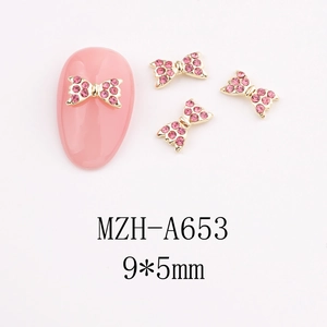 Macro detail of 9x5mm pink rhinestone bow nail charms with gold-plated base for DIY art