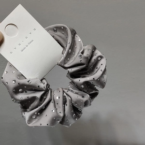 Macro shot of grey satin scrunchie with rhinestones on a white display card