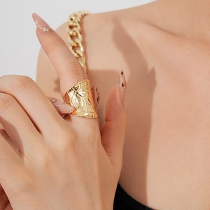 Gros plan d'une bague large dorée irrégulière en métal texturé portée par un mannequin