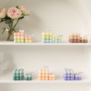 Pastel bubble cube scented candles in large and small sizes on minimalist white shelves
