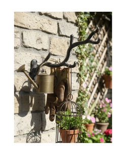 Gancio da parete rustico in ghisa a forma di ramo con attrezzi da giardino su mattone