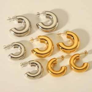 Flat lay of chunky gold and silver hollow hoop earrings in various sizes on beige background