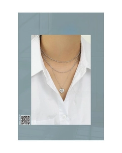 Detailed macro view of layered silver necklace featuring a heart-shaped relief pendant