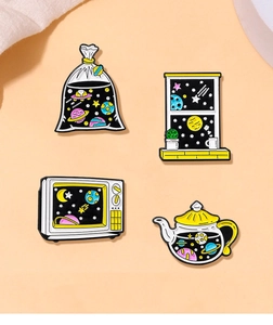 Detailed close-up of colorful outer space enamel pins with TV and teapot shapes